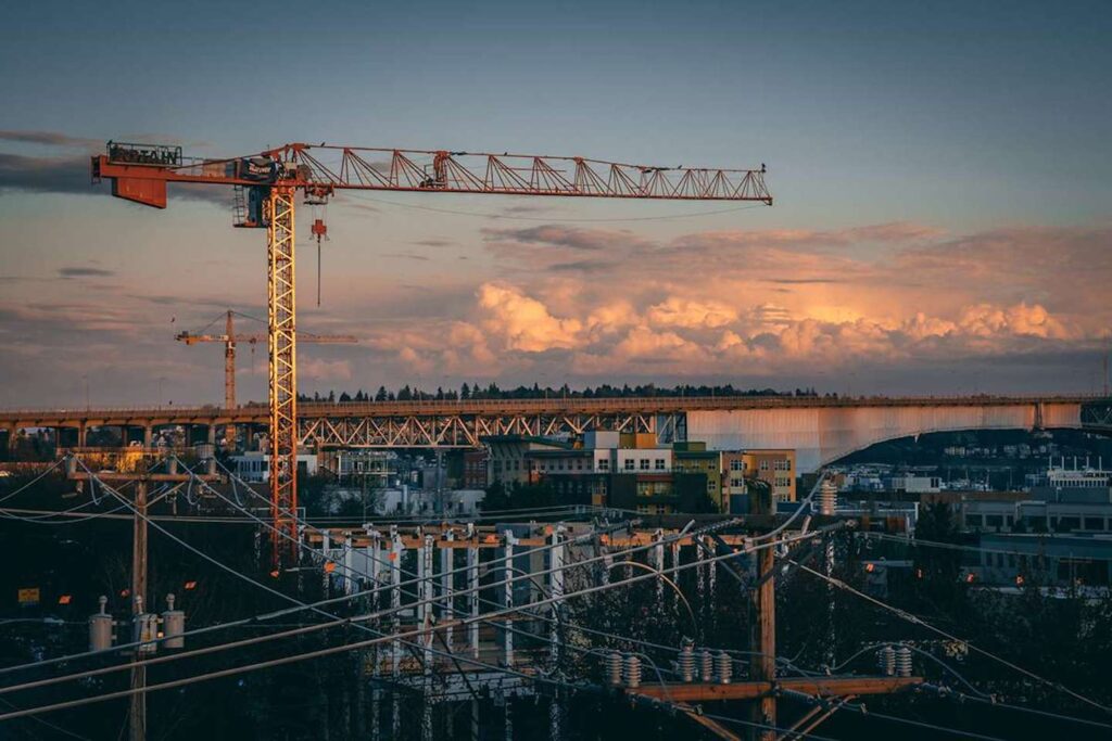 Construction site with two cranes, one in the foreground and one in the background.