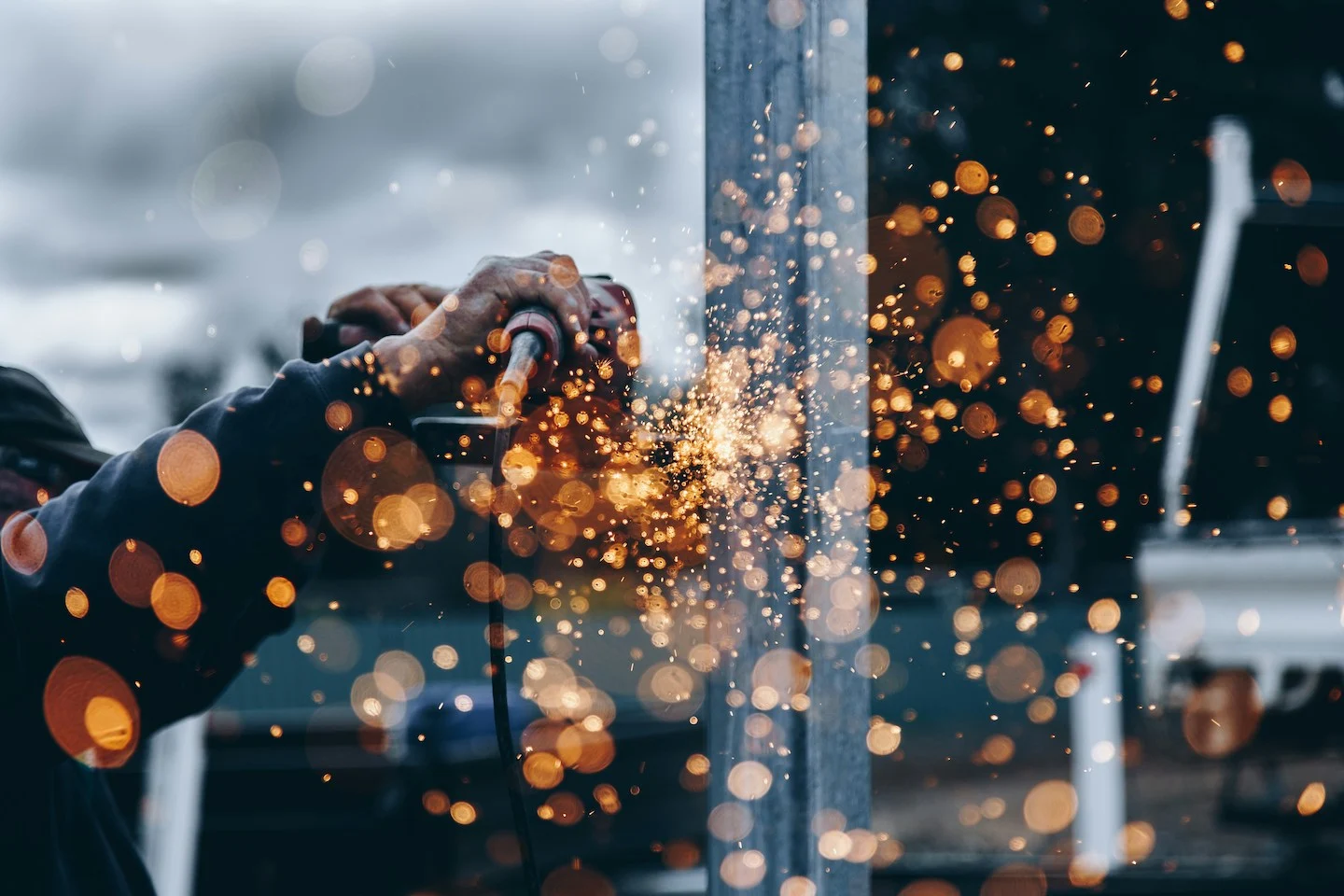 Construction work cutting steel with sparks flying in the foreground.