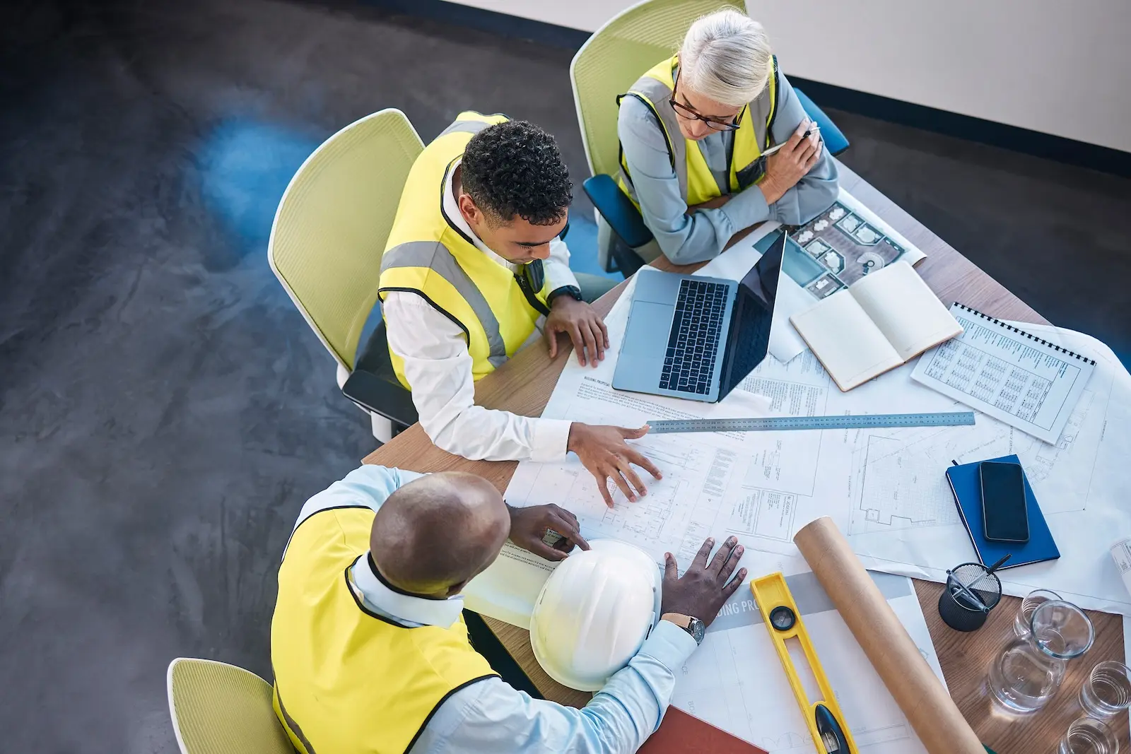 Three people having a construction meeting to ensure safety before starting a project.