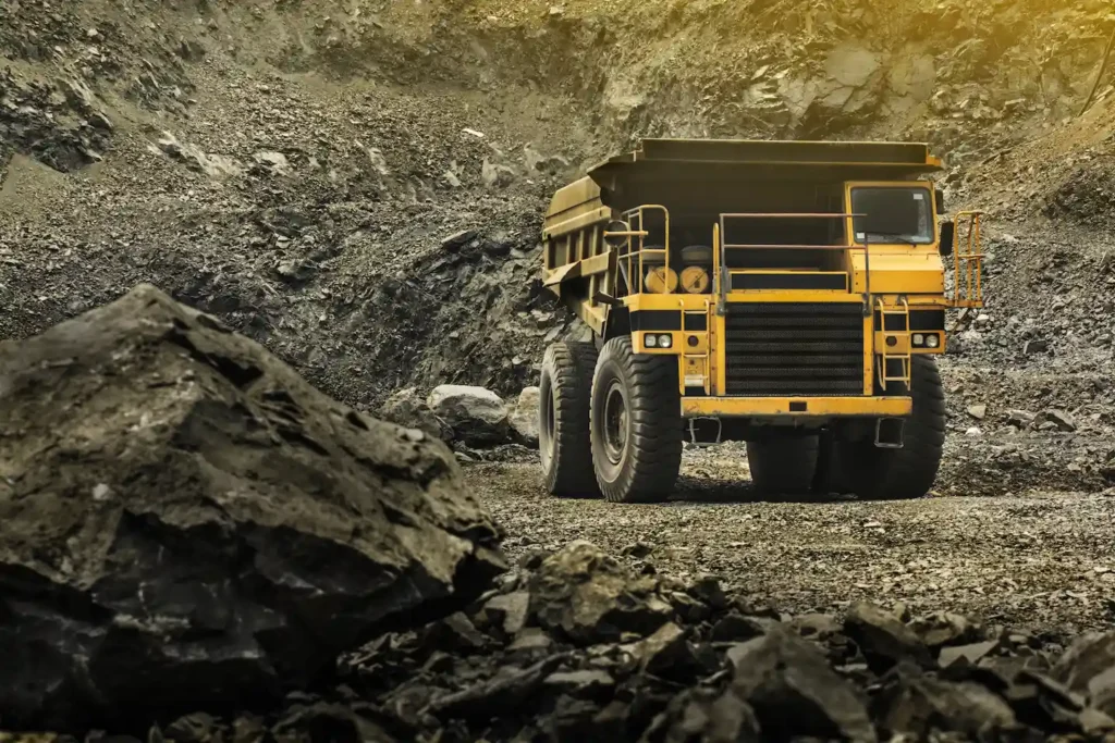 Yellow mining vehicle driving through a rocky, gray valley.