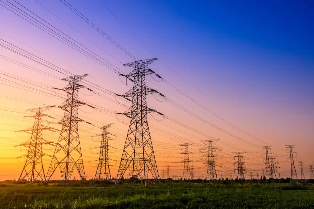 Power lines in a grassy field at sunset.