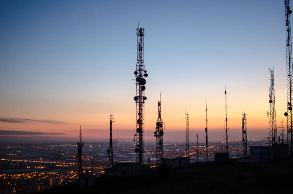 Telecom tower cells and antennas on hill above city.